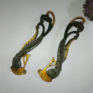 May include: Two ornate gold and green metal door handles shaped like peacocks with intricate details.