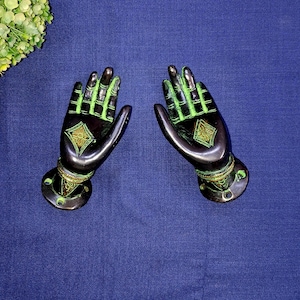 Op de afbeelding: Twee bronzen handsculpturen met groene accenten. De handen zijn in een uitnodigend gebaar, met ingewikkelde details op de handpalmen en vingers. De basis van elke hand heeft een decoratieve ring en montagegaten.