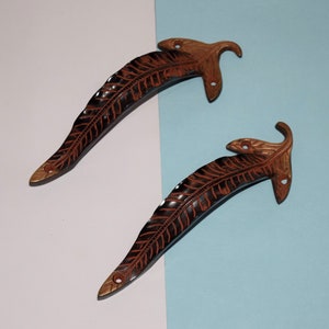 Könnte beinhalten: Zwei verzierte, blattartige Türklinken mit dunkelbrauner Oberfläche und goldenen Akzenten.
