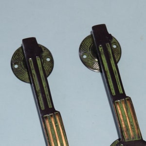 May include: Two antique-style door handles with a black and green finish. The handles have a decorative design with gold accents.