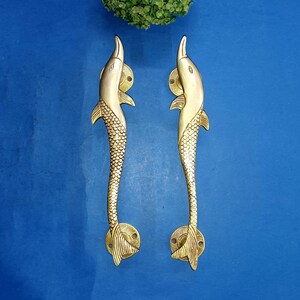 May include: A pair of gold-toned dolphin door handles. The handles are detailed with scales and fins.