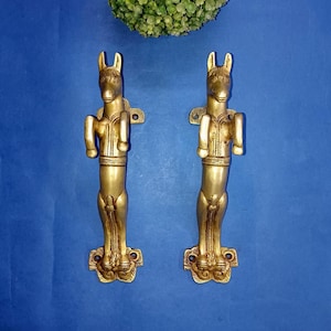 May include: A white ceramic mug with a black handle and the text "But First, Coffee" in a black, bold font. The mug is on a white surface.