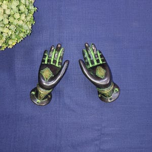 May include: A pair of decorative brass door handles shaped like hands with green and gold accents.
