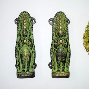 Peut inclure: Deux poignées de porte en métal vert et or avec des sculptures complexes d'une divinité à plusieurs têtes. Les poignées ont la forme d'une figure debout avec les mains jointes en prière.