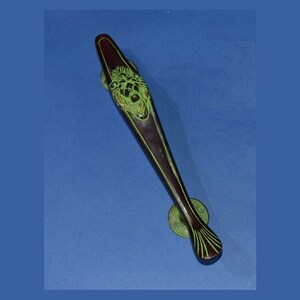 Puede incluir: Una larga manija de puerta marrón oscuro con un diseño de cabeza de león verde. La manija tiene un extremo decorativo en forma de abanico.