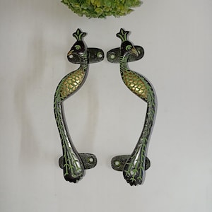 May include: A pair of peacock-shaped door handles with green and gold accents. The handles are made of metal and have a black finish.