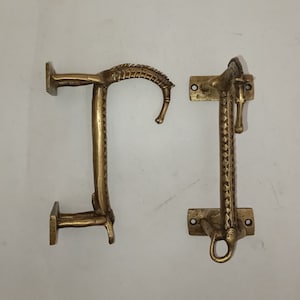 May include: Two ornate brass door handles with a decorative design. The handles are in the shape of a stylized animal with a curved handle.