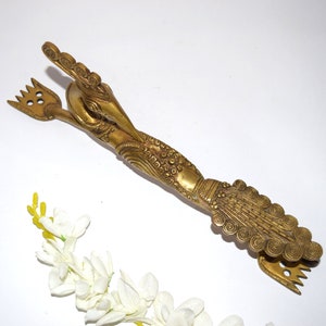 Peut inclure: Un ustensile de service en métal doré en forme d'oiseau avec des détails complexes. L'ustensile a deux pointes à chaque extrémité.