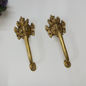 Peut inclure: Deux poignées de porte en laiton ornées d'un motif de tête d'éléphant. Les poignées sont ornées de sculptures complexes et ont une finition dorée.