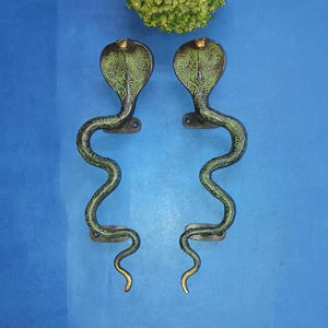 May include: A pair of black and green door handles shaped like a cobra snake. The handles are made of metal and have a detailed design.