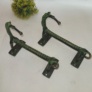 Puede incluir: Dos tiradores de puerta de metal verde antiguo con diseños de cabeza de caballo. Los tiradores son ornamentados y tienen un acabado desgastado.