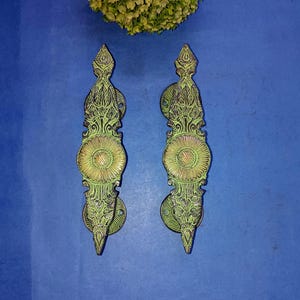 May include: A pair of ornate green and gold door handles with intricate floral designs. The handles are made of metal and have a traditional style.