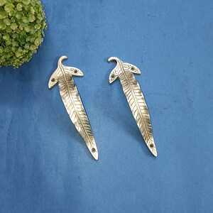 May include: Two gold-toned metal leaf-shaped door pulls with a detailed leaf design.