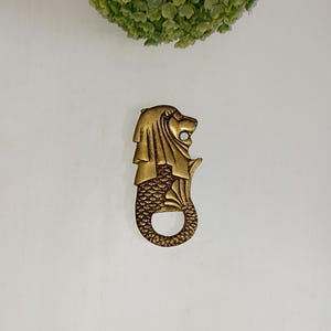 Apribottiglie con simboli di divinità del leone egizio / Accessori per bevande, utensili per feste e decorazioni in ottone
