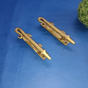 Peut inclure: Deux poignées de porte dorées en forme de lézards avec des motifs détaillés. Les poignées sont sur un fond bleu.