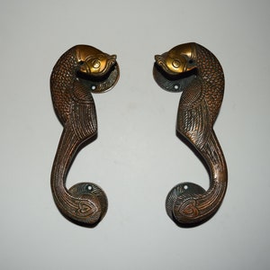 Puede incluir: Un par de tiradores de puerta de latón adornados con forma de pavo real con detalles intrincados. Los tiradores son de color bronce oscuro con detalles dorados.