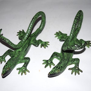 May include: Two green metal lizard wall hooks. The lizards are curled up with their tails forming a hook.