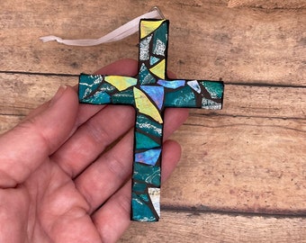 Peut inclure: Une décoration de croix en mosaïque avec un schéma de couleurs vert, bleu, jaune et blanc. La croix est munie d'un ruban blanc attaché au sommet pour la suspendre.