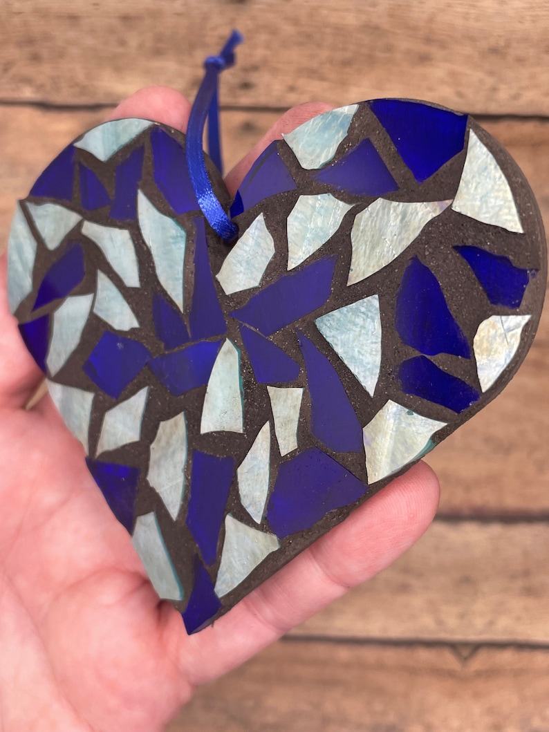 May include: A blue and white mosaic heart ornament with a blue string for hanging.
