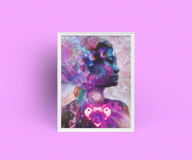 Op de afbeelding: Een ingelijste print van een vrouwen gezicht met een galaxie en sterren op de achtergrond. De vrouw heeft een blauw gezicht en een roze hart in haar borst. De achtergrond is zacht roze.