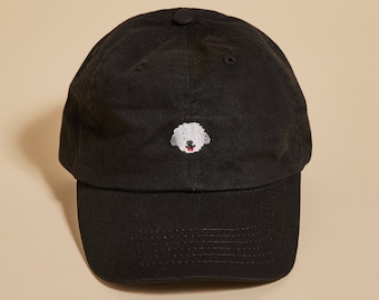 May include: A black baseball cap with a white embroidered dog face on the front.