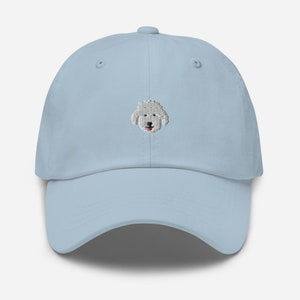 May include: A light blue baseball cap with an embroidered white dog face on the front.