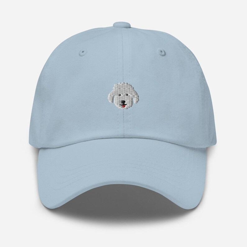May include: A light blue baseball cap with an embroidered white dog face on the front.