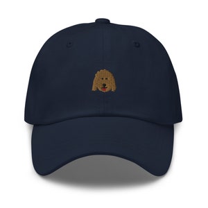May include: A navy blue baseball cap with an embroidered brown dog face.