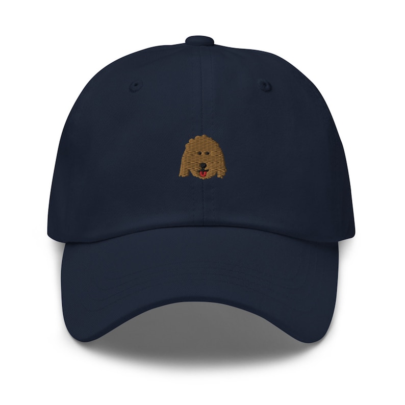 May include: A navy blue baseball cap with an embroidered brown dog face.