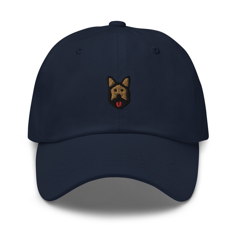 May include: A navy blue baseball cap with an embroidered brown and black German Shepherd dog face with a red tongue.