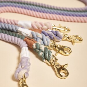 May include: Five colorful cotton rope dog leashes with gold metal clasps. The leashes are in shades of pink, purple, blue, green, and cream.
