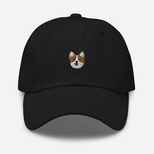 K&ouml;nnte beinhalten: Eine schwarze Baseballkappe mit einem gestickten Bild eines braunen und wei&szlig;en Hundes mit herausgestreckter rosa Zunge.