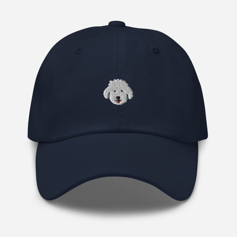 May include: A navy blue baseball cap with an embroidered white poodle face.