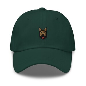 May include: A dark green baseball cap with an embroidered image of a German Shepherd dog with a brown and black coat and a red tongue.
