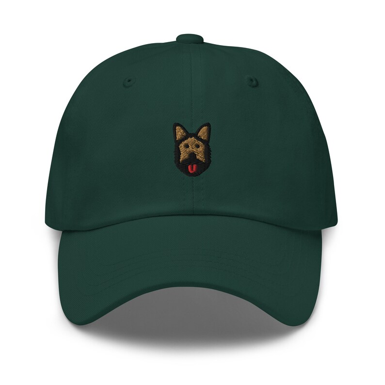 May include: A dark green baseball cap with an embroidered image of a German Shepherd dog with a brown and black coat and a red tongue.