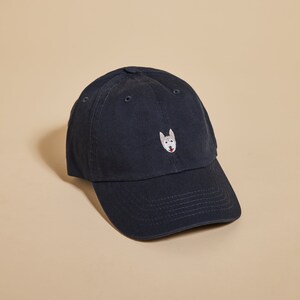 May include: A dark blue baseball cap with an embroidered white husky face on the front.