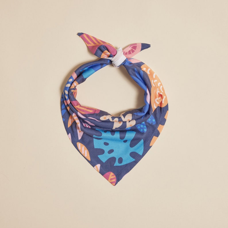 May include: A blue bandana with a colorful floral and leaf pattern. The bandana is tied in a knot at the top.