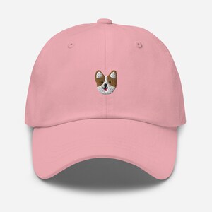 K&ouml;nnte beinhalten: Eine rosafarbene Baseballkappe mit einem gestickten Bild eines braunen und wei&szlig;en Hundes mit einer rosa Zunge.