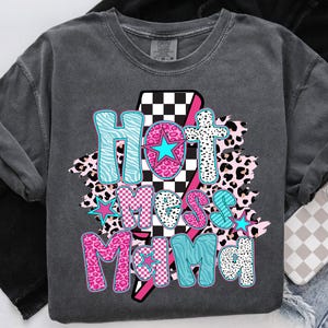May include: A gray t-shirt with a graphic design that says "Hot Mess Mama" in pink, blue, and black letters. The graphic design includes a checkered pattern, animal print, and stars.