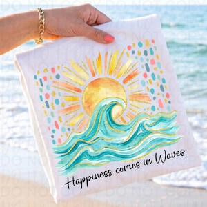 Op de afbeelding: Witte strandlaken met een aquarelontwerp van een zon, golven en de tekst "Happiness comes in Waves". De zon is geel en oranje met gouden glitteraccenten. De golven zijn turquoise met gouden glitteraccenten.