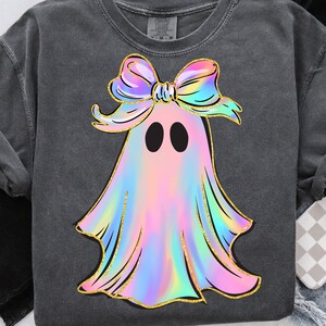 May include: Dark grey sweatshirt featuring a colorful ghost design. The ghost has a rainbow-colored body, black eyes, and a large bow. The design is outlined in gold glitter.