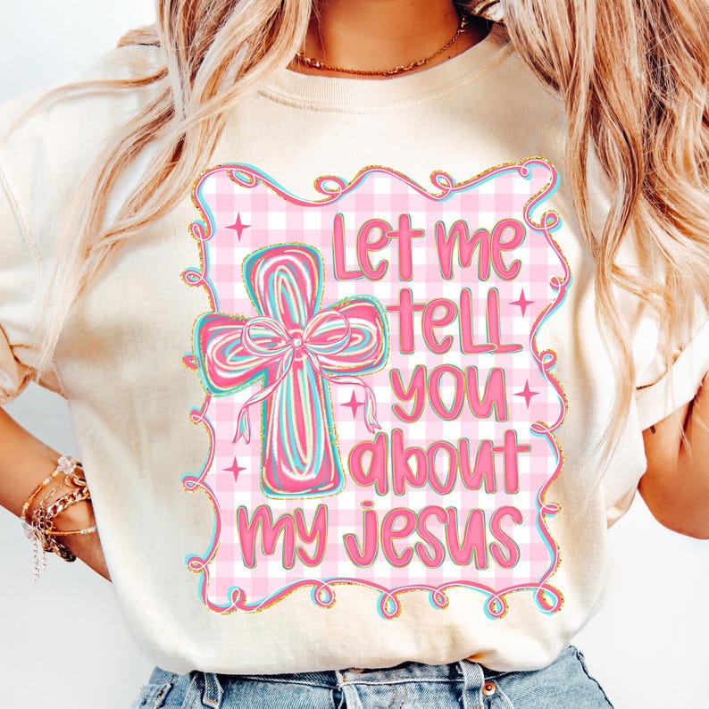 May include: Cream-colored t-shirt featuring a pink and white gingham design with a cross and the text "Let me tell you about my Jesus" in pink. The cross has a pink bow with blue and pink stripes.