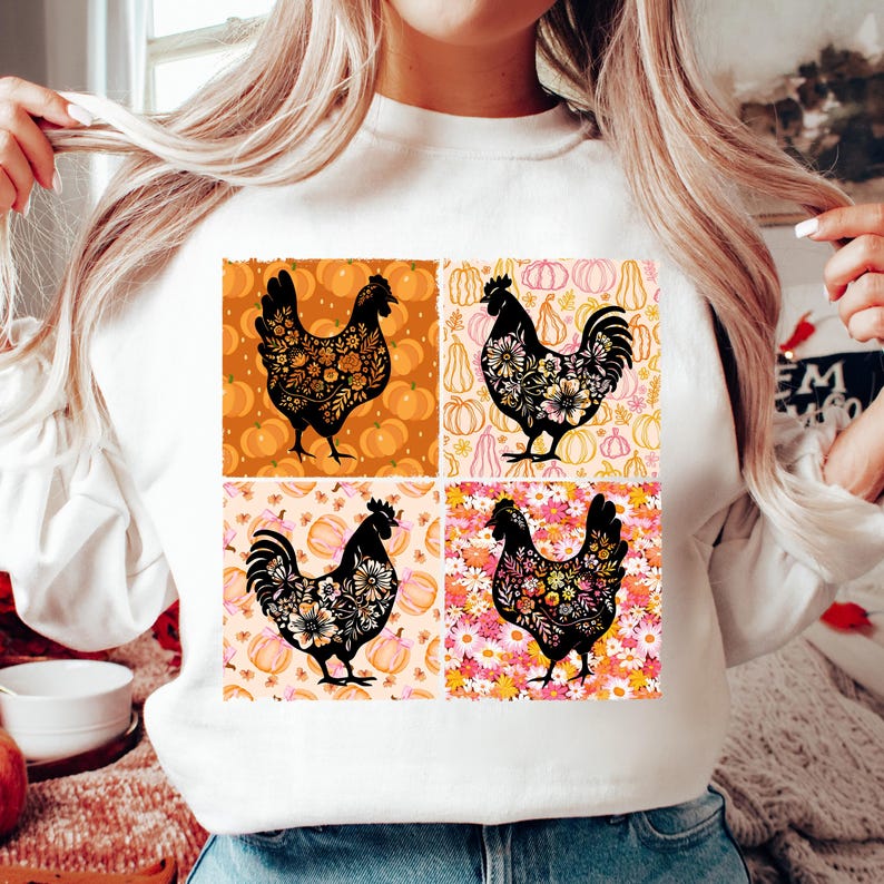 May include: White sweatshirt featuring a four-panel design with black chicken silhouettes filled with floral patterns. Each panel has a different background, including pumpkins and floral prints. The sweatshirt is a fall-themed apparel item.