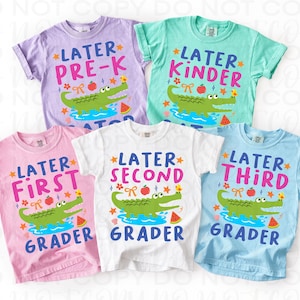K&ouml;nnte beinhalten: Eine Auswahl an bunten T-Shirts f&uuml;r Kinder mit Schulmotiven. Jedes Shirt zeigt das Wort "Later" gefolgt von einer Klassenstufe, einem Cartoon-Alligator, einem Apfel und einer Wassermelone. Die Shirts sind in verschiedenen Farben erh&auml;ltlich, darunter Rosa, Blau und Wei&szlig;.