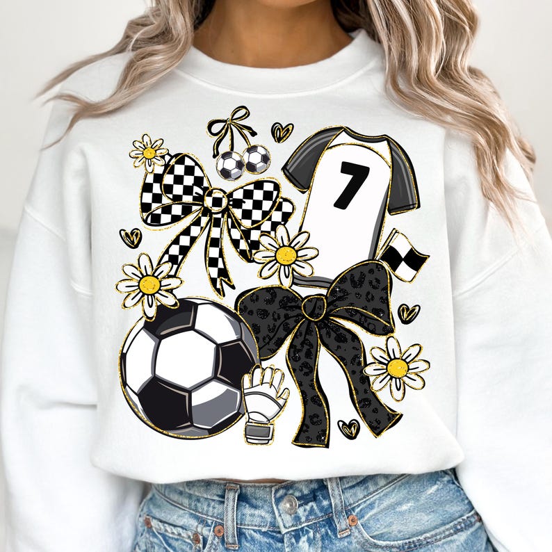 May include: White sweatshirt with a soccer-themed design. Features a soccer ball, jersey with the number 7, bows, flowers, and a soccer glove. The design incorporates black, white, and gold accents, creating a playful and sporty aesthetic.