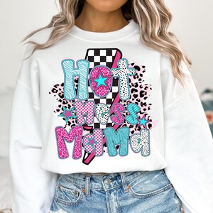 May include: White sweatshirt with a graphic design of a lightning bolt with the text "Hot Mess Mama" in pink, blue, and black with a checkered pattern and animal print.