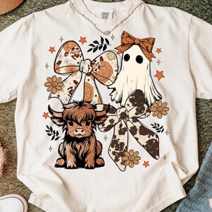 Op de afbeelding: Cr&egrave;mekleurig T-shirt met een grillig ontwerp. De afbeelding bevat een Schotse hooglander, een spook en decoratieve strikken met bloemen- en koeienhuidpatronen. Accentueren met oranje sterren en bloemelementen. Het shirt heeft een relaxte pasvorm.