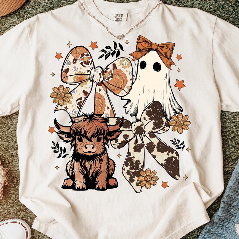 Op de afbeelding: Cr&egrave;mekleurig T-shirt met een grillig ontwerp. De afbeelding bevat een Schotse hooglander, een spook en decoratieve strikken met bloemen- en koeienhuidpatronen. Accentueren met oranje sterren en bloemelementen. Het shirt heeft een relaxte pasvorm.