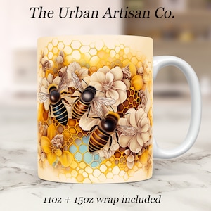 May include: White ceramic mug with a design of three bees and flowers on a honeycomb background. The text "The Urban Artisan Co." is at the top of the mug. The text "11oz + 15oz wrap included" is at the bottom of the mug.