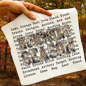 May include: A white pillow with the words "HUNTING SEASON" in large, camouflage-patterned letters. The pillow also features a camouflage bow and a list of hunting-related terms in black text.